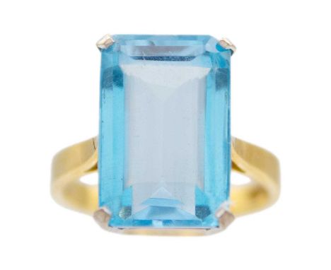 An 18ct yellow and white gold, blue topaz set cocktail ring. The rectangular step cut topaz of 10.6ct estimated weight, Sheff