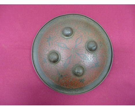 11 1/2 inch diameter, brass shield.  The face chiselled with floral and scroll patterns and filled with black and red enamel.