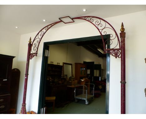 A RED PAINTED IRON ARCH CRESTED BY A LANTERN RECEIVER, THE SIDE POLES WITH GILT DETAILS AND AN OVAL CAST WITH THE MAKERS NAME