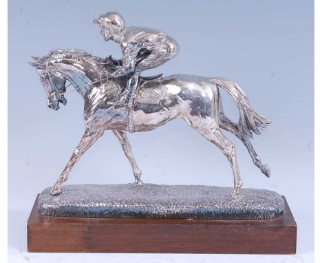 A contemporary silver clad model of a racehorse with jockey up, on a textured oval base and oak plinth, designed by David Gee