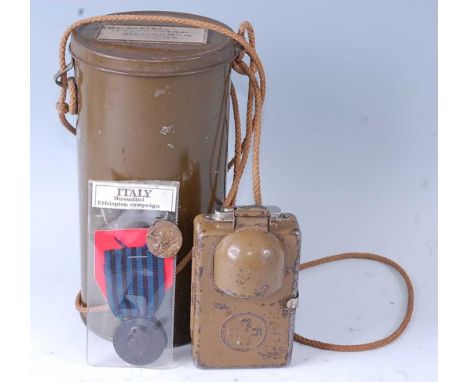 A WW II signal lamp, the front with hinged cover over the lens, the back with leather strap and marked Elves Mendrisio, dated