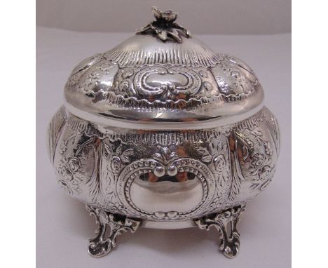 A continental white metal trinket box of lobed oval form chased with flowers and leaves, the domed hinged cover with floral f