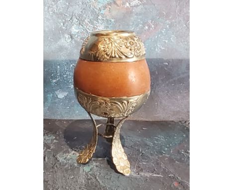 A South American silver coloured metal mounted calabash gourd mate cup, loft legs, 14cm high 