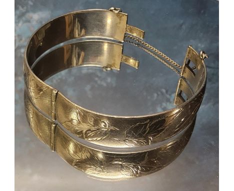 A silver hinged bangle, engraved &amp; chased with foliage, clasp faulty, Harrod's Stores Ltd, Birmingham, 1966, 49.08g; 