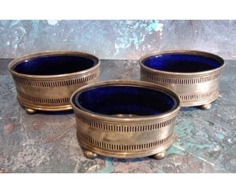 A set of three George V silver open oval&nbsp; salts, pierced bands, blue glass liners, bun feet, 6.5cm wide, Birmingham 1918