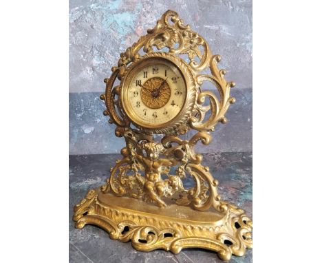 A Victorian brass mantel clock, the dial with Arabic numerals, pierced leafy scroll and cherub case, oval base with C and Scr