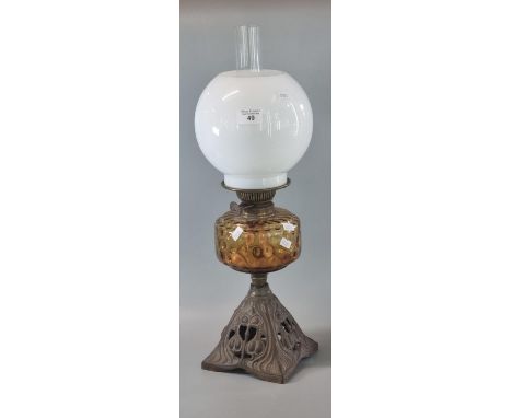 Early 20th century double oil burner lamp having globular opaline glass shade above an amber glass reservoir on a cast iron b