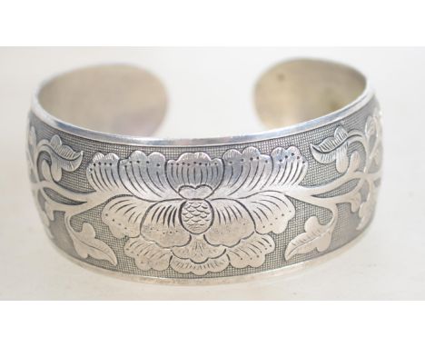 A heavy silver bangle bracelet having engraved foliate and grid decoration bearing Chinese silver marks. Weighs 35.2 grams an