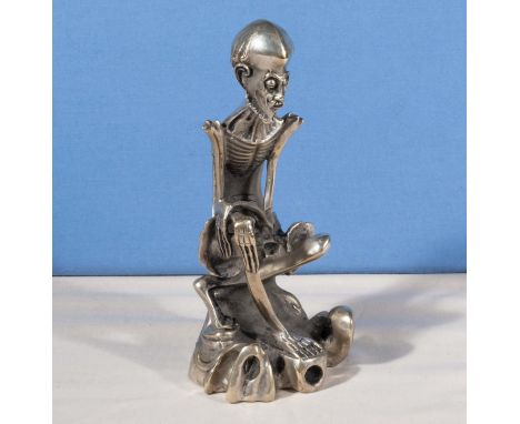 An unusual Chinese silvered metal figure of a Deity sitting on a tree trunk, seal marks to base