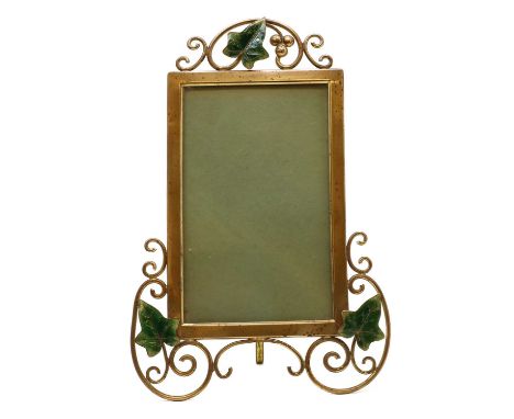 A brass and enamelled photograph frame, c.1900, with a wire mounted frames, mounted with green enamelled leaves, with an ease