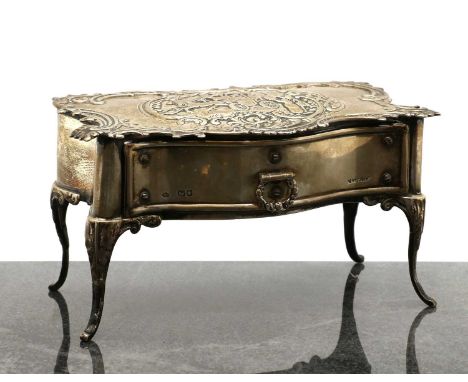 A silver jewellery box,by William Comyns, London, in the form of a commode, the embossed top depicting figures standing befor