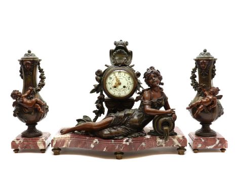 A spelter clock garniture,the enamel dial marked 'A. Tetart, Boulogne S/ Mer', above a figure of a reclining woman, leaning o