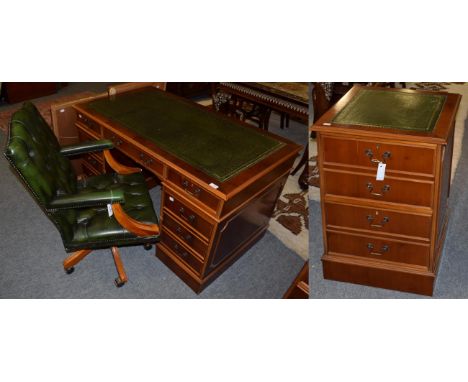 A reproduction yew wood pedestal desk; a green button leather executive high back chair; and a yew wood filing cabinet with l