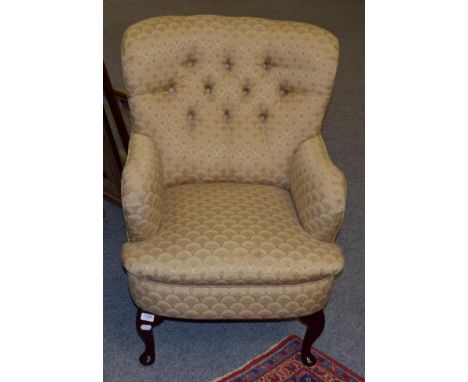A modern button back armchair upholstered in gold and floral fabric