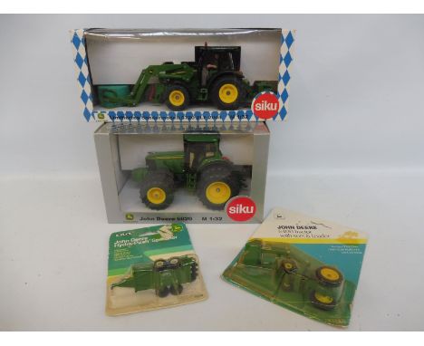 Two Siku 1/32 scale boxed model tractors and two carded John Deere models. 