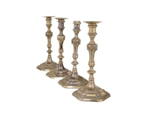 A SET OF FOUR GEORGE III  SILVER CANDLESTICKS with banded sconce on leaf and shell knops and shaped and gadrooned hexagonal f