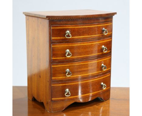 AN EDWARDIAN INLAID MAHOGANY BOW-FRONT MINIATURE CHEST OF DRAWERS, fitted with four graduated drawers with stringing, raised 