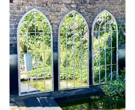 ARCHITECTURAL GARDEN MIRRORS, a set of three, 160cm high, 67cm wide, arched aged metal frames with overlaid detail. (3) 