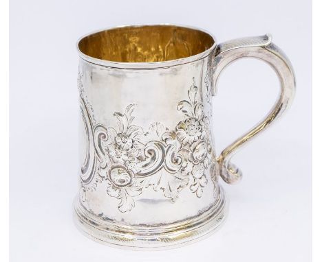 An 18th Century silver tapering cylindrical mug, with gilt interior and embossed floral design, vacant cartouche, hallmarked 