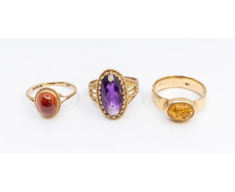 A collection of three stone set 9ct gold rings to include an elongated amethyst ring, stone app4ox 15 x 8mm, size Q, a dark a