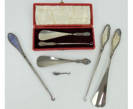 A collection of early 20th Century silver mounted button hooks and shoe horns including guilloche enamel and a cased set, the