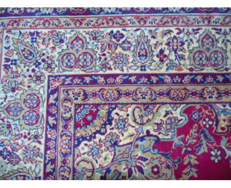 A Persian Style Wool Carpet with red field, stylised floral detail, set within geometric running borders €100-140