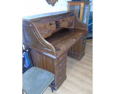 An Oak Tambour Top Writing Desk, having a fitted interior with frieze drawer,  flanked by four & three pedestal drawers eithe