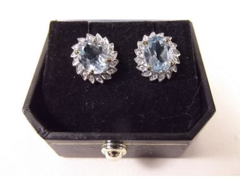 A pair of 9 carat white and yellow gold earrings set aquamarines in diamond chip surround