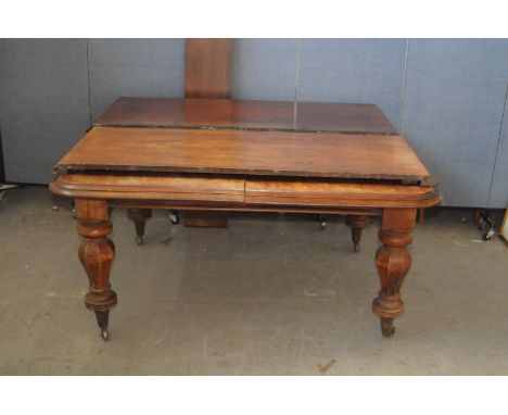 An interesting William IV period mahogany extending dining table, having four large baluster supports on casters, with square