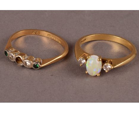 An 18ct gold opal and diamond dress ring, the central oval cut opal flanked by two round cut diamonds, together with another 