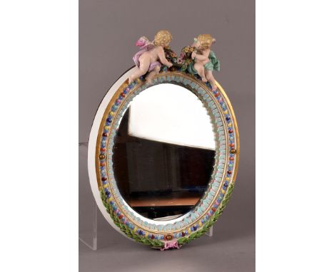 A vintage Dresden porcelain framed mirror, surmounted by a pair of cherubs and painted in bright colours with laurel swag to 