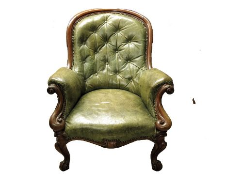 A Victorian carved mahogany and leather upholstered armchair, spoon back form, button backed with serpentine scroll moulded a