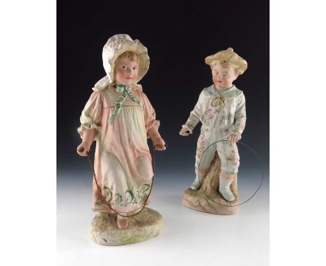 Two Gebruder Heubach bisque figures of children playing, the boy with stick and hoop, the girl modelled skipping, 33cm high (