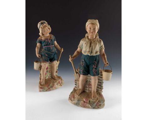 A pair of Gebruder Heubach bisque figures of beach children, both in dark teal costumes, encrusted, modelled holding buckets 