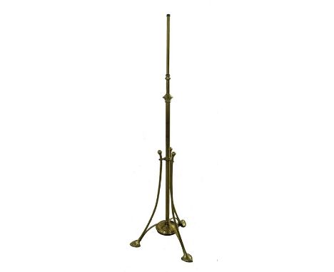 An Arts and Crafts brass adjustable standard lamp, circa 1900, tubular construction on three cylindrical legs terminating in 