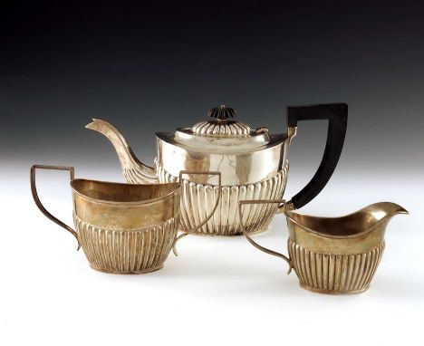 A George V silver three piece tea set, A J Zimmerman, Birmingham 1919, half reeded boat form, with ebony handle and finial, 1