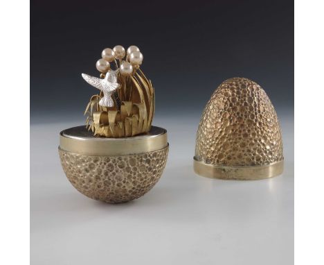 Stuart Devlin, a novelty silver gilt surprise egg, London 1977, the crater textured body with plain band, opening to reveal a