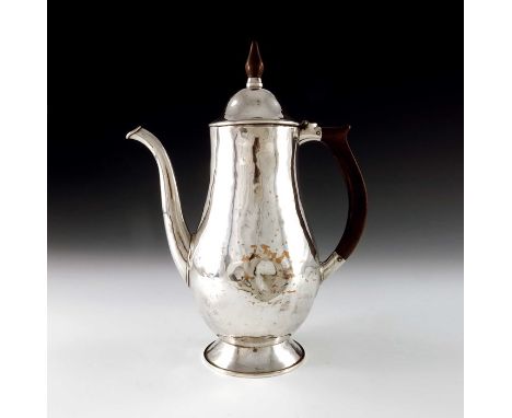 An Arts and Crafts silvered copper coffee pot, circa 1920s, planished, footed baluster form with conical domed lid and wooden