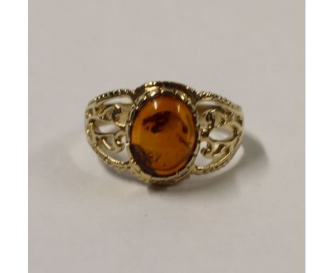 A yellow metal ladies' dress ring with oval cabochon amber stone and fancy filigree shoulders, size R, approx 3.1g.