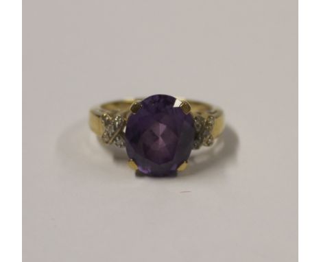 A 9ct yellow gold ladies' dress ring, central oval amethyst-coloured stone with chip diamond to the shoulders in cross format