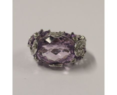 A 14ct white gold ladies' dress ring with large oval facet-cut amethyst within a scrolling white stone mount, floral amethyst