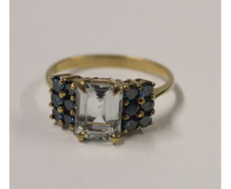 A gold ladies' dress ring with old-cut central pale blue tourmaline and six blue stones to either shoulder, size S, approx 3.