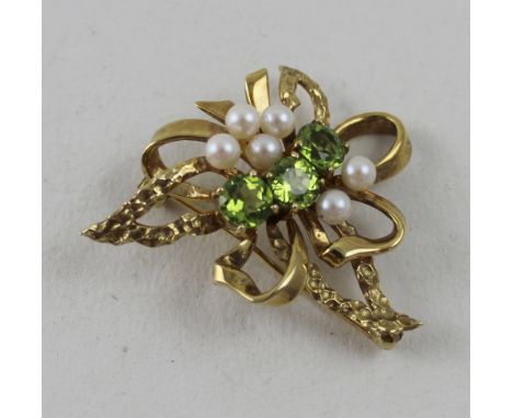 A 9ct yellow gold bow brooch set with small pearls and three peridots to the centre, approx 7g.