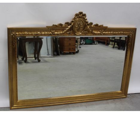 A very large Regency-style gilded overmantel mirror with bow, ribbon and acanthus leaf decoration to the top within an acanth