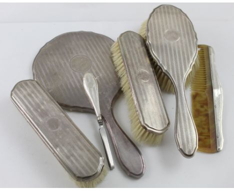 A hallmarked silver five-piece vanity set, hand mirror, ladies' brush, two gentlemen's brushes and a comb, White &amp; Hawkin