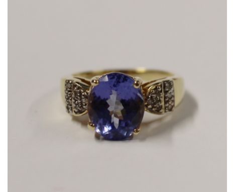 An 18ct yellow gold ladies' dress ring, oval facet-cut blue stone (possibly tanzanite), with tiny diamond chips to the should