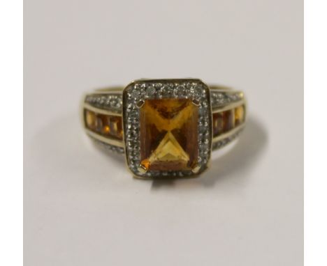 A 9ct yellow gold ladies' dress ring with amber emerald-cut tanzanite and white stone chips to the shoulder, size R, approx 5