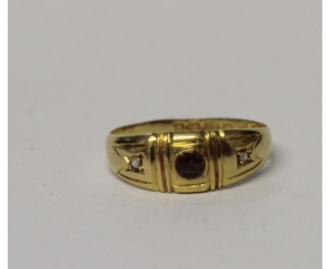 An 18ct yellow gold ladies' dress ring set with a single central red stone and tiny diamonds to either side, size M, approx 1