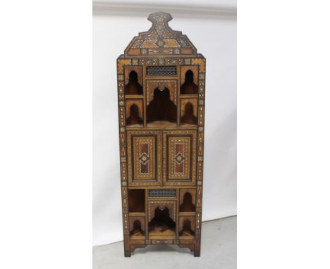 A late 19th century Indian hardwood floor standing corner cupboard, highly decorated with inlay and mother of pearl, stylised