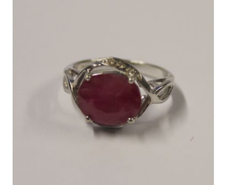 A 9ct white gold ladies' dress ring with oval facet-cut single ruby and small white stone surround, size M, approx 4.7g.